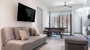 A modern living room with a grey sofa, a flat-screen TV mounted on the wall, and a ceiling fan. - Quinto Sol Tulum (Tulum)