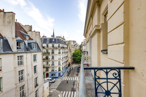 A narrow street with buildings on either side, a pedestrian crossing, and a blue railing. - The cellarman - Bright & Calm by Mon Petit Faré (Paris)