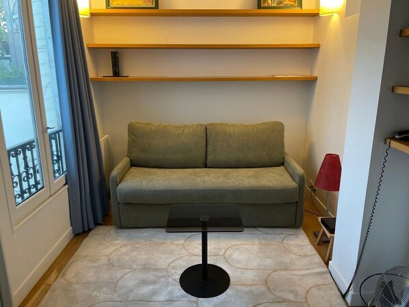 A small living area with a sofa, a small table, and a standing fan. - The cellarman - Bright & Calm by Mon Petit Faré (Paris)