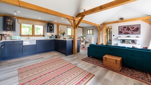 A spacious kitchen with dark blue cabinets, a white countertop, and wooden beams on the ceiling. - The Lodge at Leigh - Luxury Cottages (Sherborne)