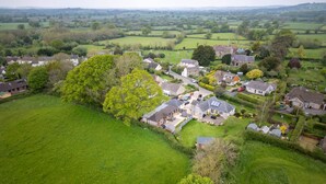 An aerial view of a residential area with houses, green fields, and a church. - The Lodge at Leigh - Luxury Cottages (Sherborne)