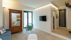 Un salon moderne avec un meuble en bois, un canapé bleu, un fauteuil vert, une table blanche et un téléviseur fixé au mur.