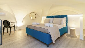 Une chambre à coucher avec un lit, une chaise, une table de chevet et un miroir rond.