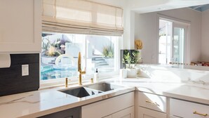 Cozinha moderna com uma janela grande, pia embutida e bancada de mármore.