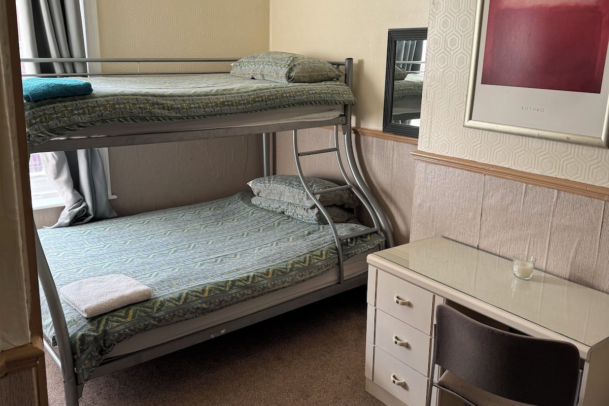 A bunk bed room with a desk and a framed picture on the wall.