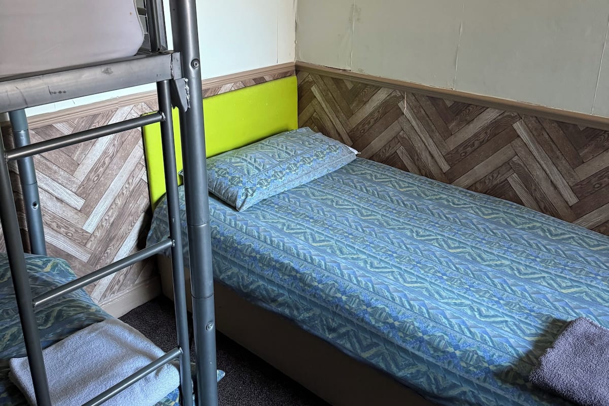 A bunk bed with a lower bunk and a single bed, both with patterned bedding.
