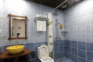 Une salle de bain avec un lavabo jaune, des toilettes, une douche avec un rideau et un miroir avec un cadre en bois.