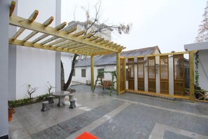 A covered outdoor area with a pergola, stone seating, and a traditional gate. - Donglai Courtyard Inn (Yangzhou)