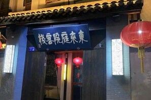 A building with a sign in Chinese characters, a traditional tiled roof, and red lanterns. - Donglai Courtyard Inn (Yangzhou)