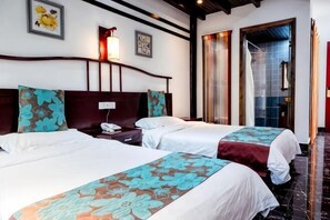 Une chambre d’hôtel avec deux lits, une table de chevet avec un téléphone, une lampe fixée au mur et une grande fenêtre donnant sur un beau paysage.