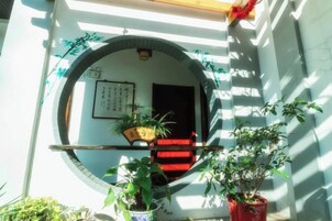 Una entrada japonesa tradicional con puerta de madera, alfombra roja y plantas en macetas.