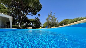 Ein klarer Pool mit Blick auf ein Gebäude und Bäume im Hintergrund.