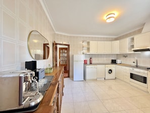 Enjoy cooking in this well-equipped kitchen with a stainless steel espresso machine, microwave, sink, and washing machine.