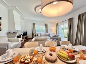 Relax in a cozy living space with a sofa, armchairs, and a fireplace, perfect for unwinding with a flat-screen TV and a delicious breakfast.