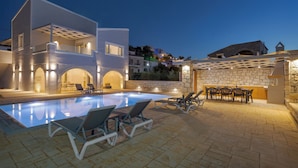 A modern pool area with lounge chairs and a stone wall.
