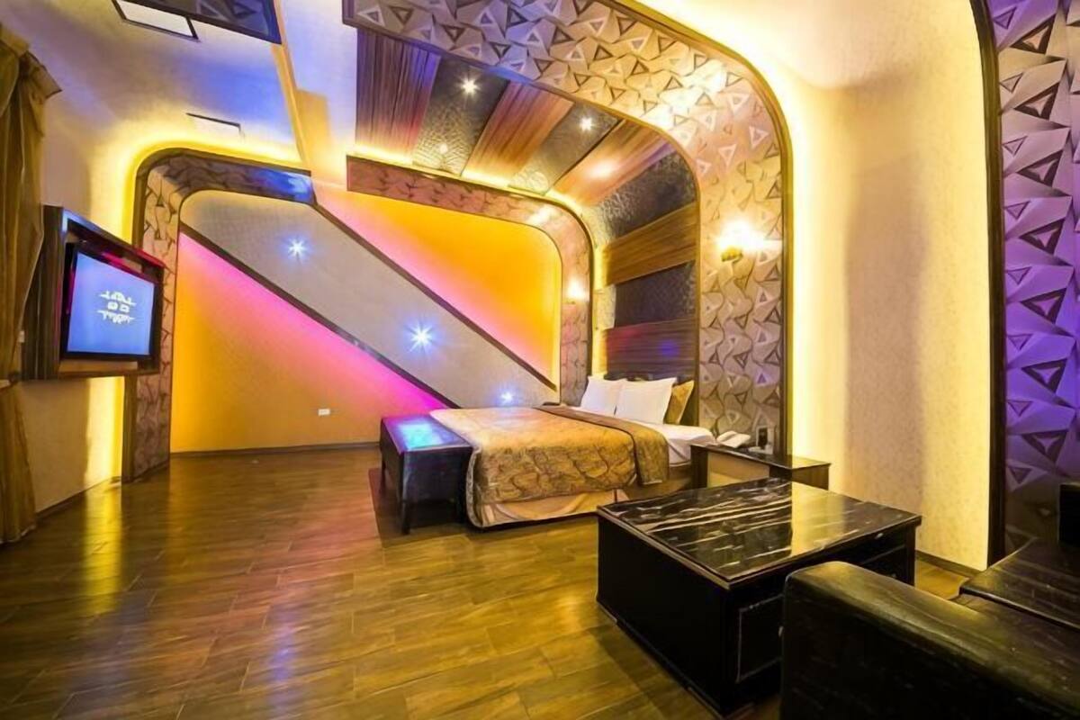 A hotel room with a bed, a TV, a desk, and a staircase.