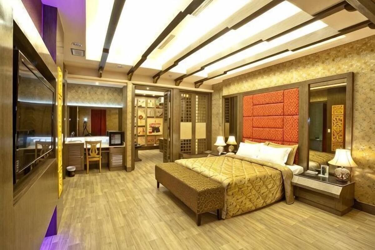 A hotel room with a large bed, a desk, a mirror, and a TV.