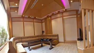 A spacious room with a large L-shaped sofa, a small table, and a television.