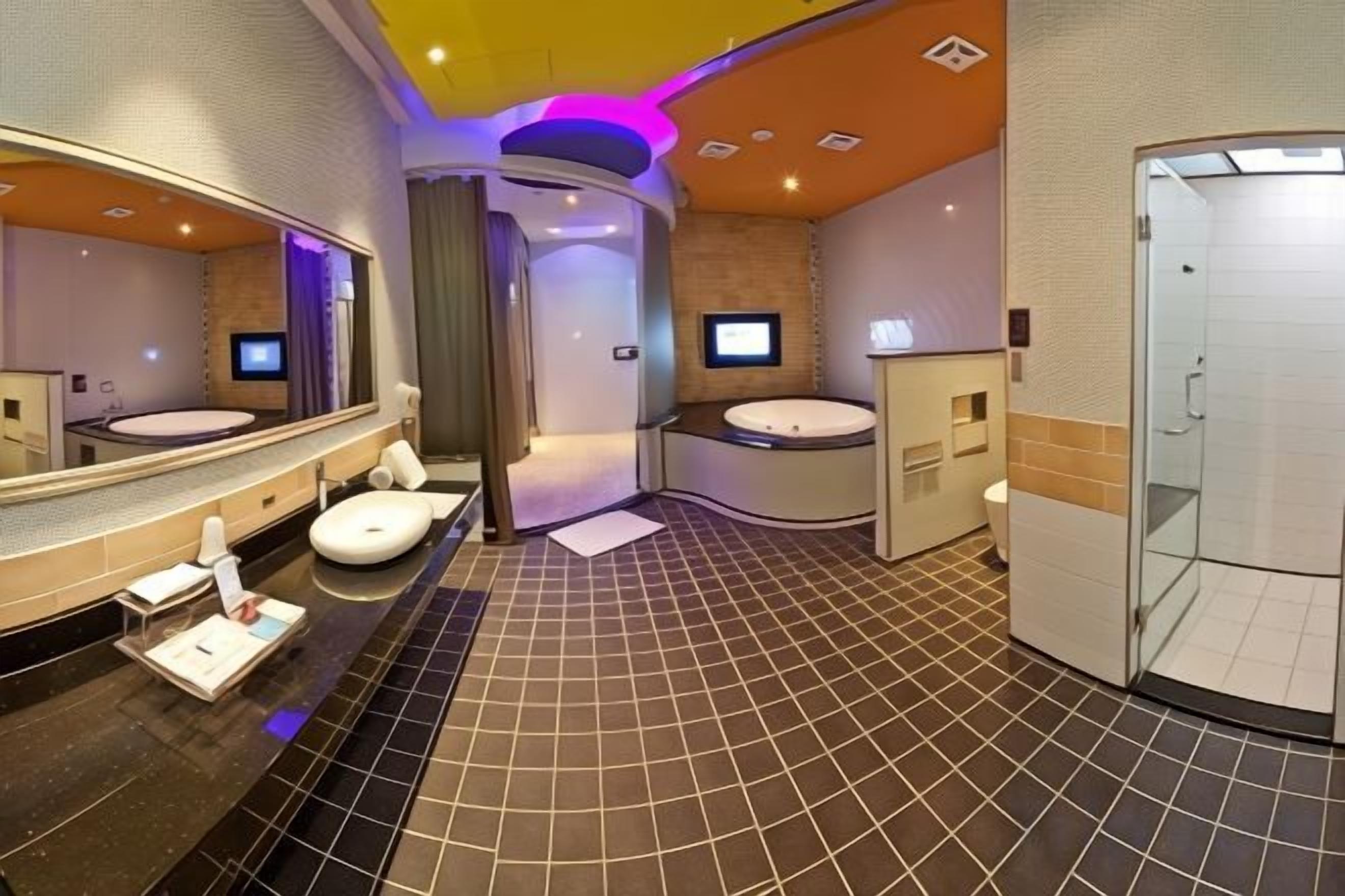 Casa de banho moderna com disposição curvada, um espelho grande, duas pias e cabine de duche em vidro.