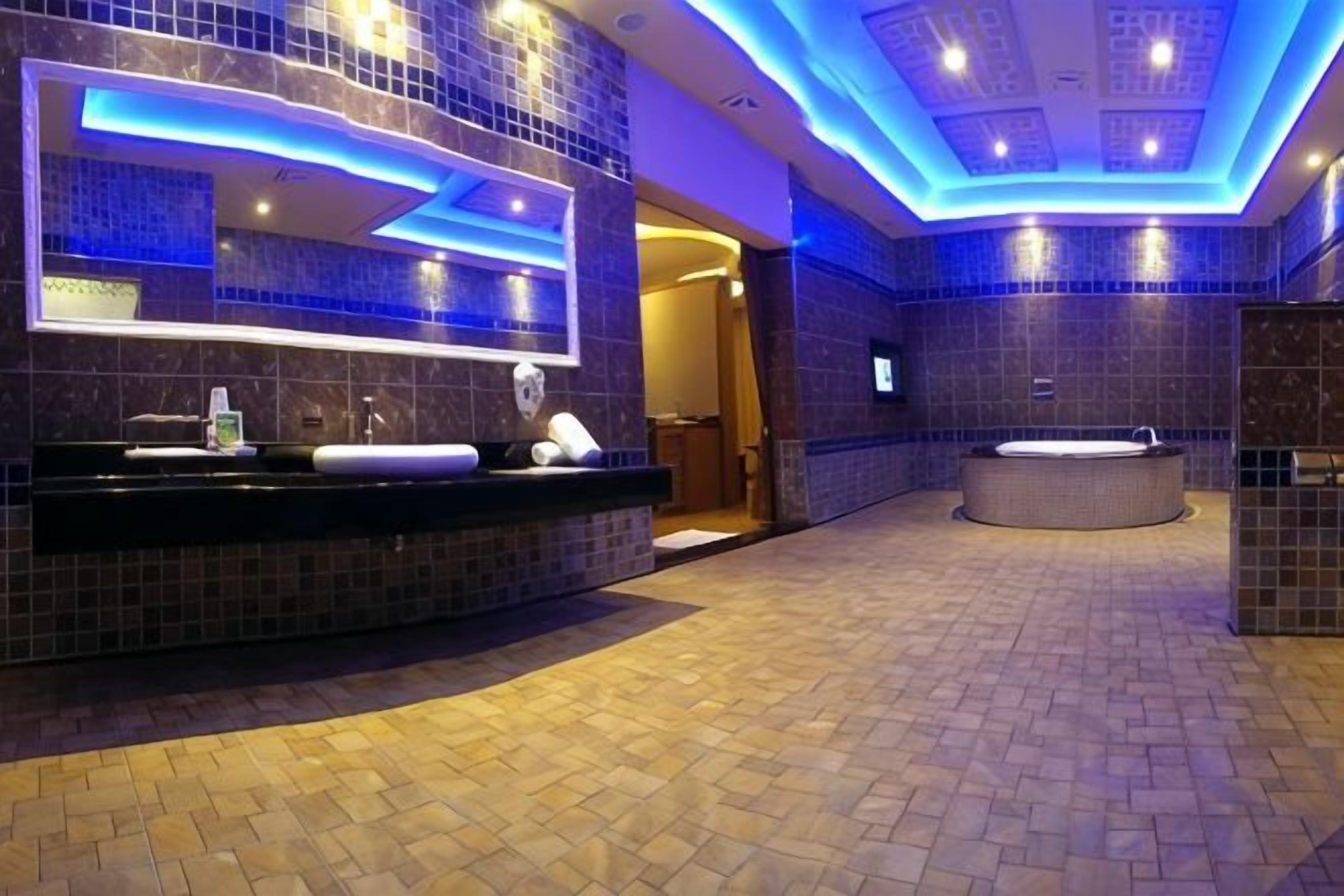 A modern bathroom with a large mirror, a sink, and a bathtub.