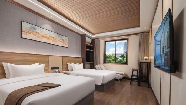 Habitación de hotel con dos camas, un ventanal grande, un televisor de pantalla plana y un cuadro en la pared.