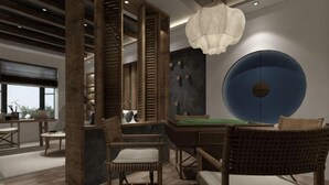 Un interior moderno con una mesa de billar, sillas de mimbre y un gran elemento decorativo azul en la pared.