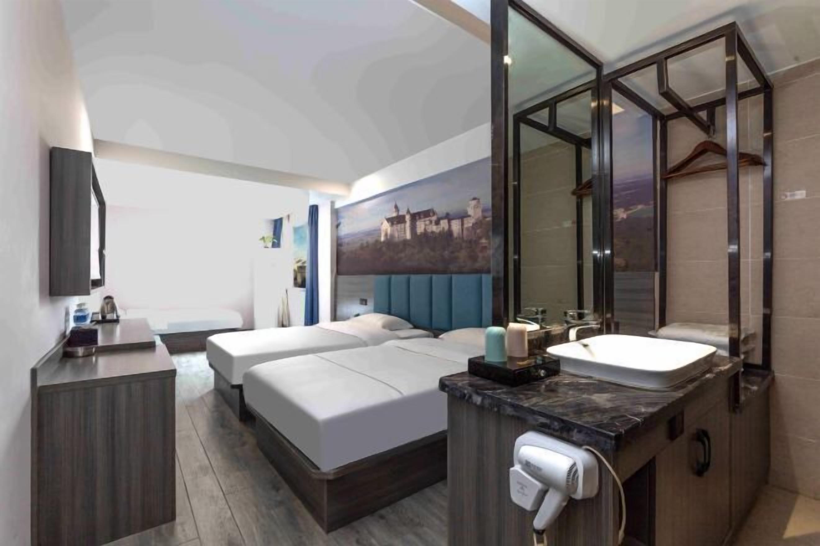 A modern hotel room with a large bed, a separate seating area, a bathroom with a large mirror, and a cityscape painting on the wall.