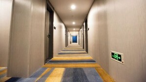En hotellkorridor med ett randigt golv, dörrar på båda sidor och en utrymningsskylt på väggen.
