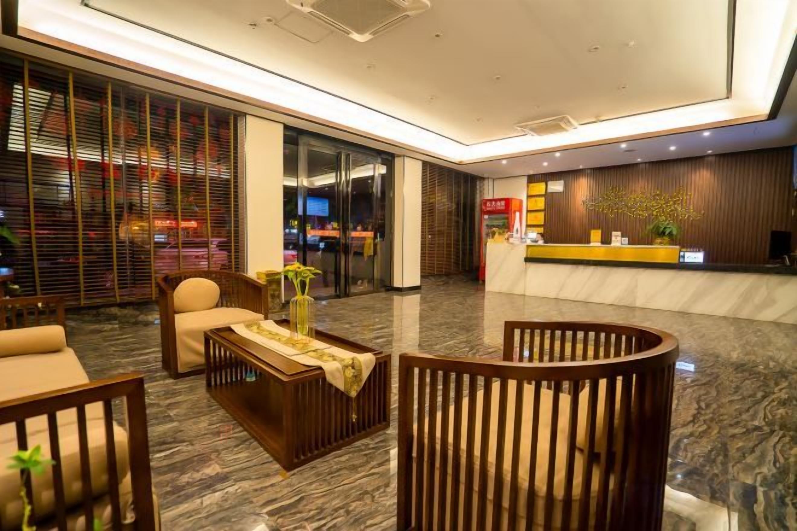 A hotel lobby with a reception desk, seating area, and a large window.