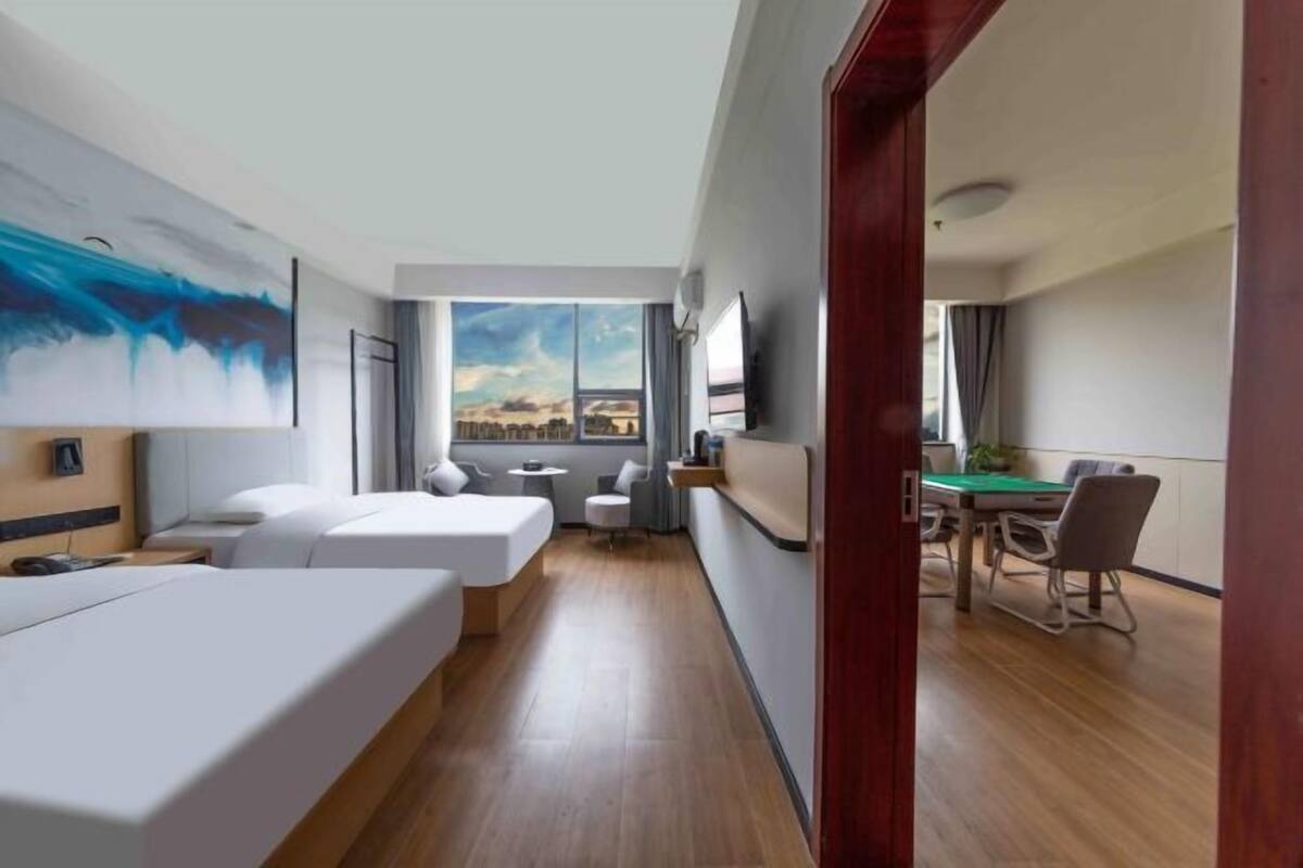 Ein modernes Hotelzimmer mit Bett, Schreibtisch, Esstisch und Blick auf die Stadt.