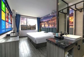 A hotel room with a bed, a desk, a TV, a bathroom with a sink and mirror, and a cityscape mural on the wall. - Yichu Hotel (Zhongxiang)