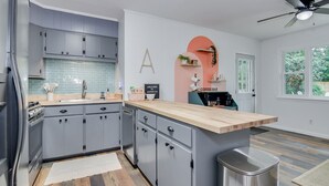 Une cuisine moderne avec des meubles gris, un plan de travail en bois et un coin café.