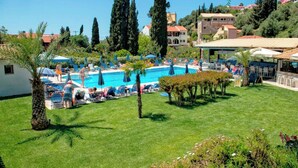 A pool area with lounge chairs and umbrellas, surrounded by greenery and buildings. - Holiday House Letta Very Quiet Location Agios Gordios Beach (Corfu)