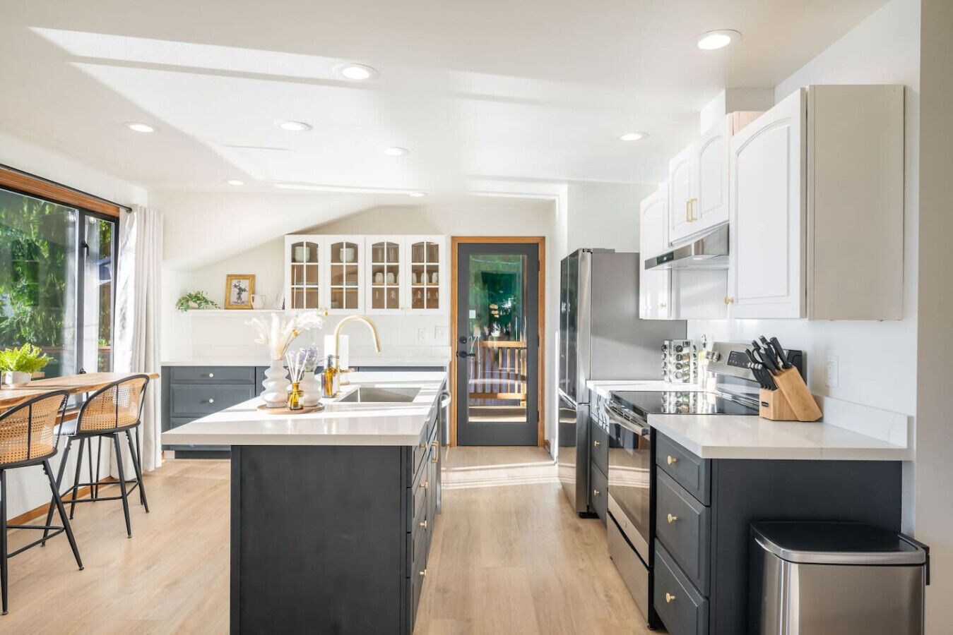 A modern kitchen with a central island, dark cabinetry, and a view into the dining area.