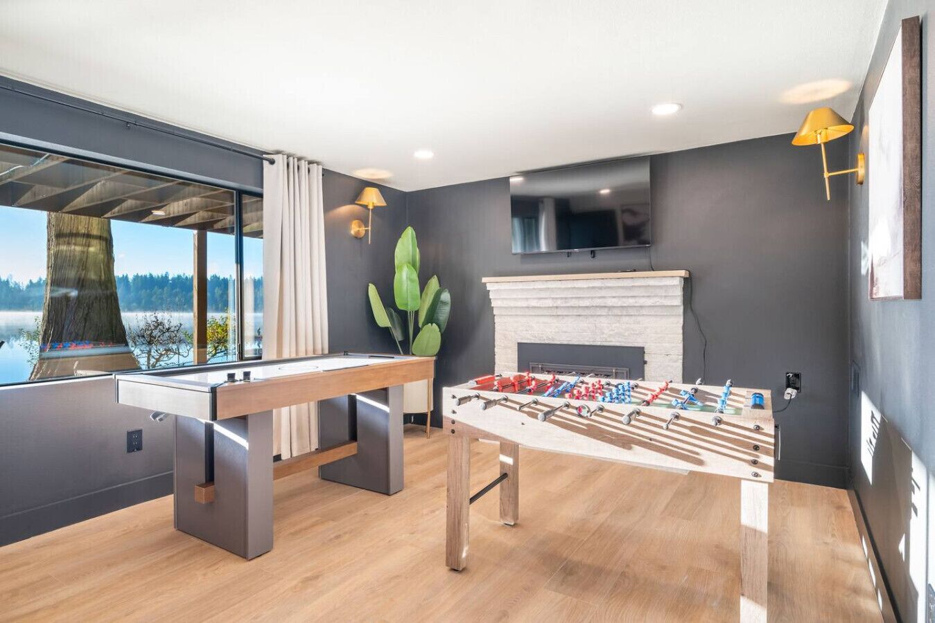 Une pièce moderne équipée d’un baby-foot, d’une table de billard et d’une cheminée.