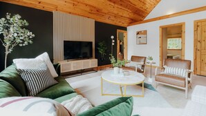 Un salon moderne avec un canapé vert, une table basse ronde et un plafond en bois.