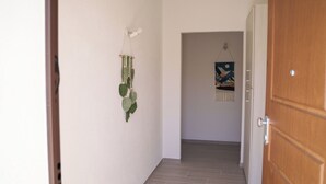 Ein Flur mit einer Holztür, einer Wandpflanze und einem hängenden Kunstwerk.