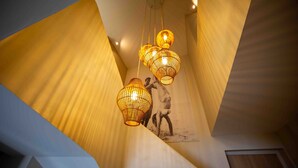 A modern interior with a geometric wall design, a staircase, and hanging wicker lamps.