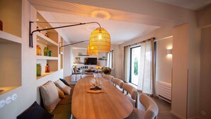 Een moderne eetruimte met een lange houten tafel, comfortabele zitplaatsen en een bijzondere hanglamp.