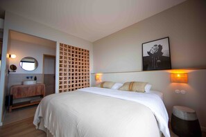 Ein Schlafzimmer mit einem großen Bett, einer Holzwand, einem runden Spiegel, einem Holzschrank und einem gerahmten Bild an der Wand.