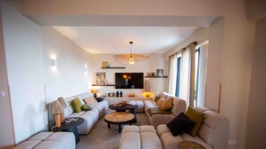 Een moderne woonkamer met een zithoek, een televisie en een eethoek.