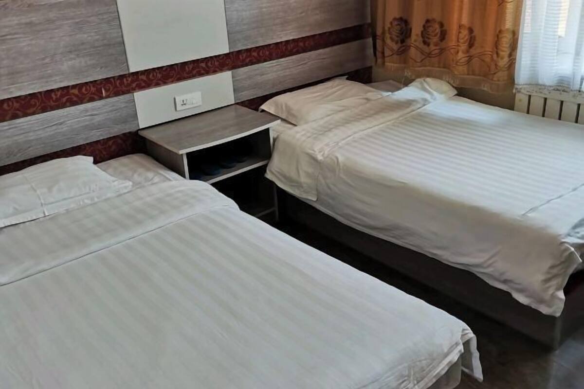 Una habitación de hotel con dos camas individuales, una mesita de noche y un armario.