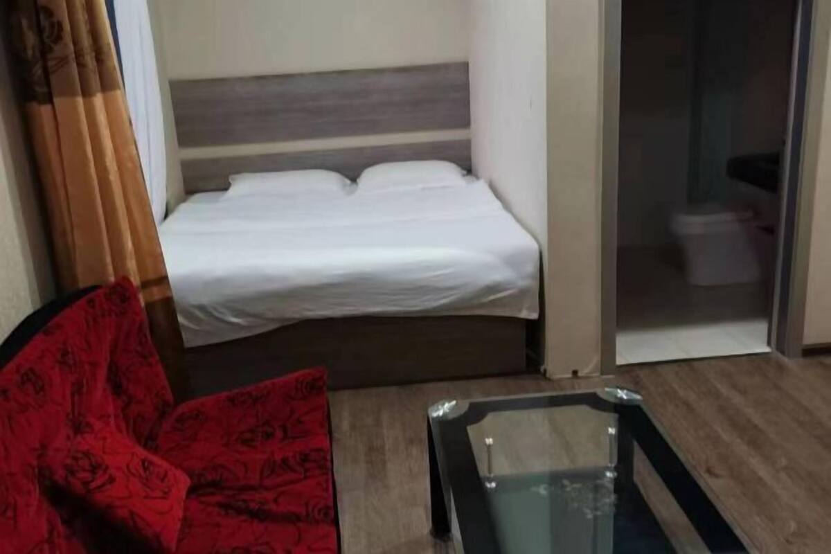 Una habitación de hotel con una cama, una silla roja y una mesa con cubierta de vidrio.