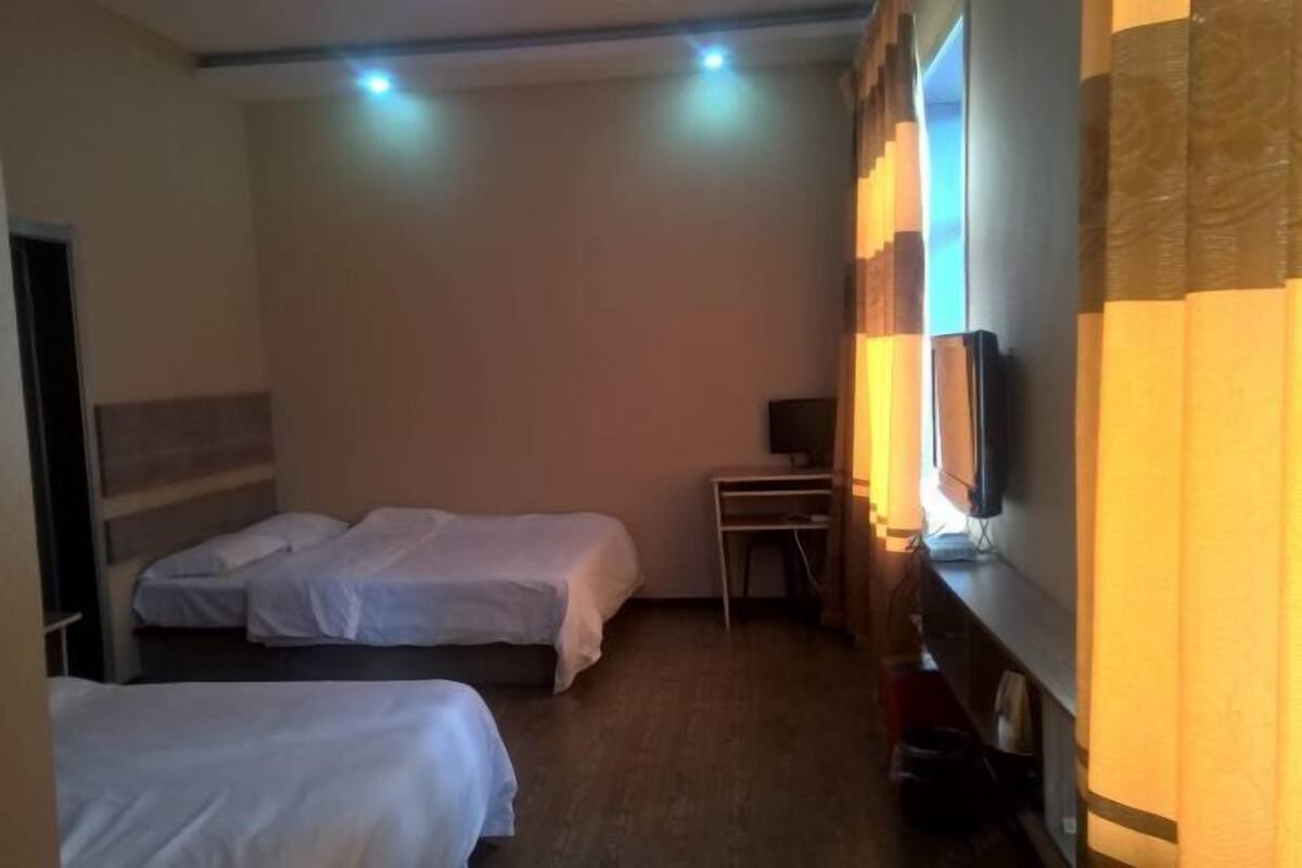 Habitación de hotel con dos camas, un escritorio, un televisor y una ventana con cortinas.