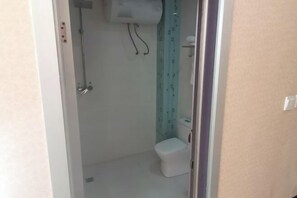 Un baño pequeño y estrecho con un inodoro y una ducha.