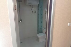 Un baño pequeño y estrecho con un inodoro y una ducha.