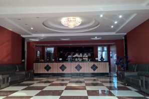 Un vestíbulo de hotel con suelo a cuadros, una recepción y una araña.