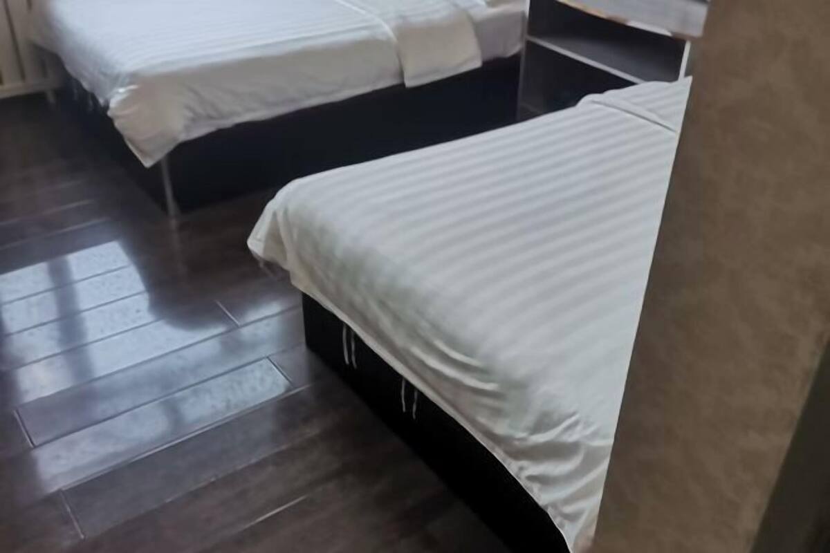 Una habitación de hotel con dos camas, suelo de madera y un cabecero oscuro.