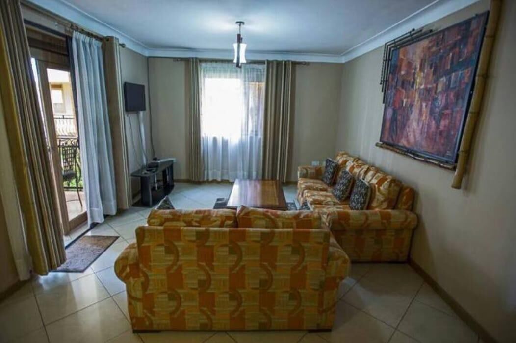 A living room with two patterned sofas, a coffee table, a TV, and a painting on the wall.