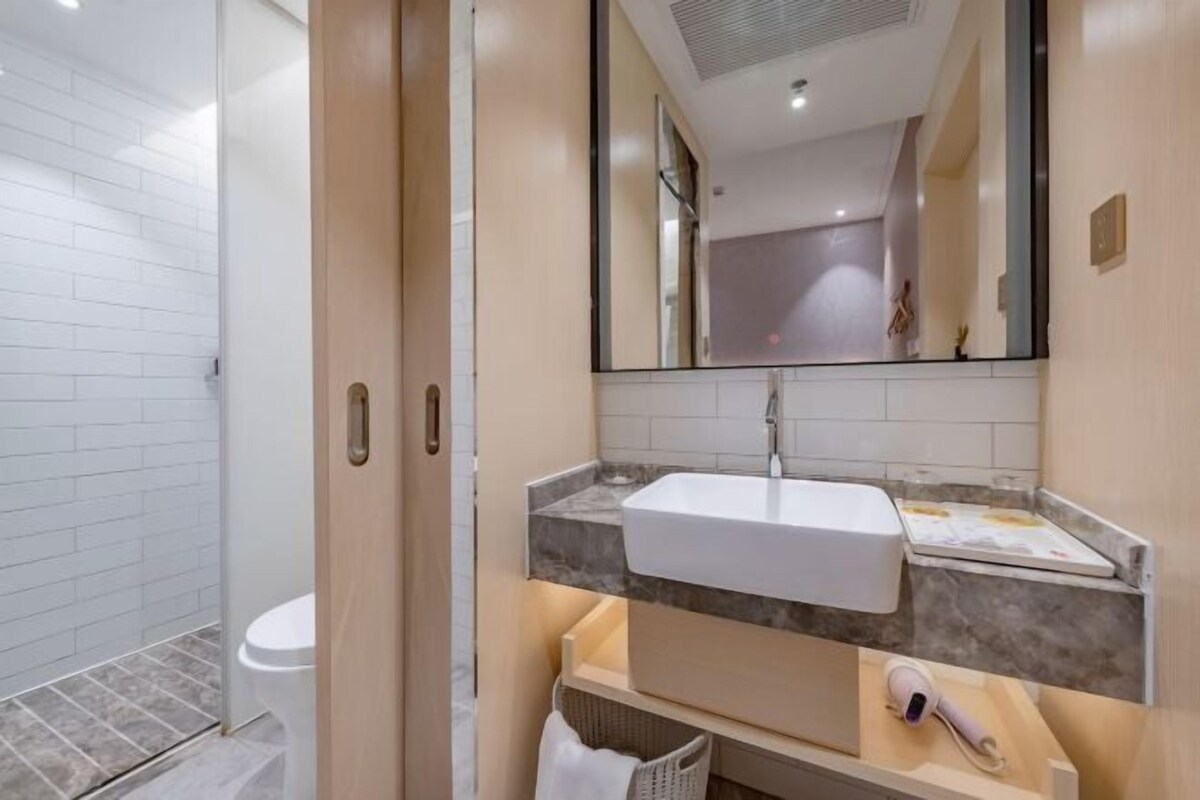 A modern bathroom with a white sink, a mirror, and a shower area.
